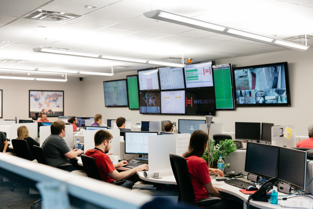 A group of Hivelocity employees sitting at desks in a room filled with monitors