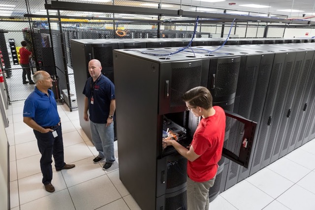 Hivelocity employee working on a server in our data center as two customers stand by
