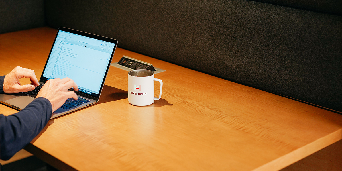 Image of a laptop sitting next to a coffee cup featuring the Hivelocity logo