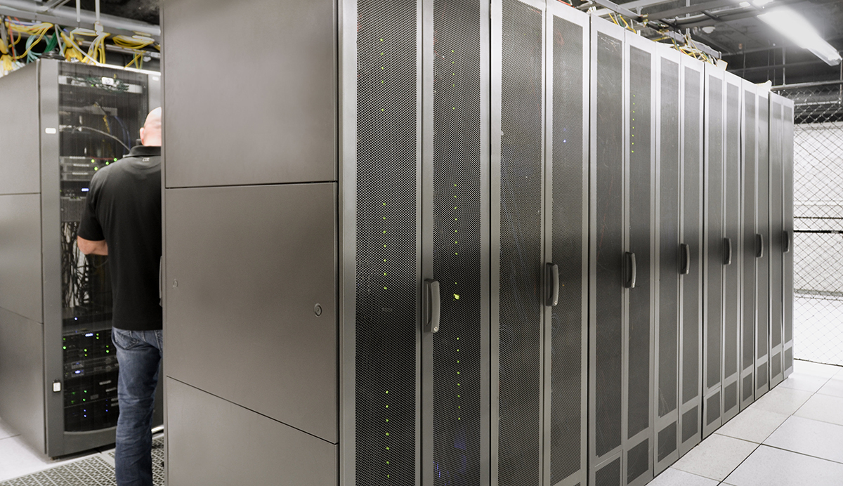 Rows of colocation cabinets with a technician working on a client's server