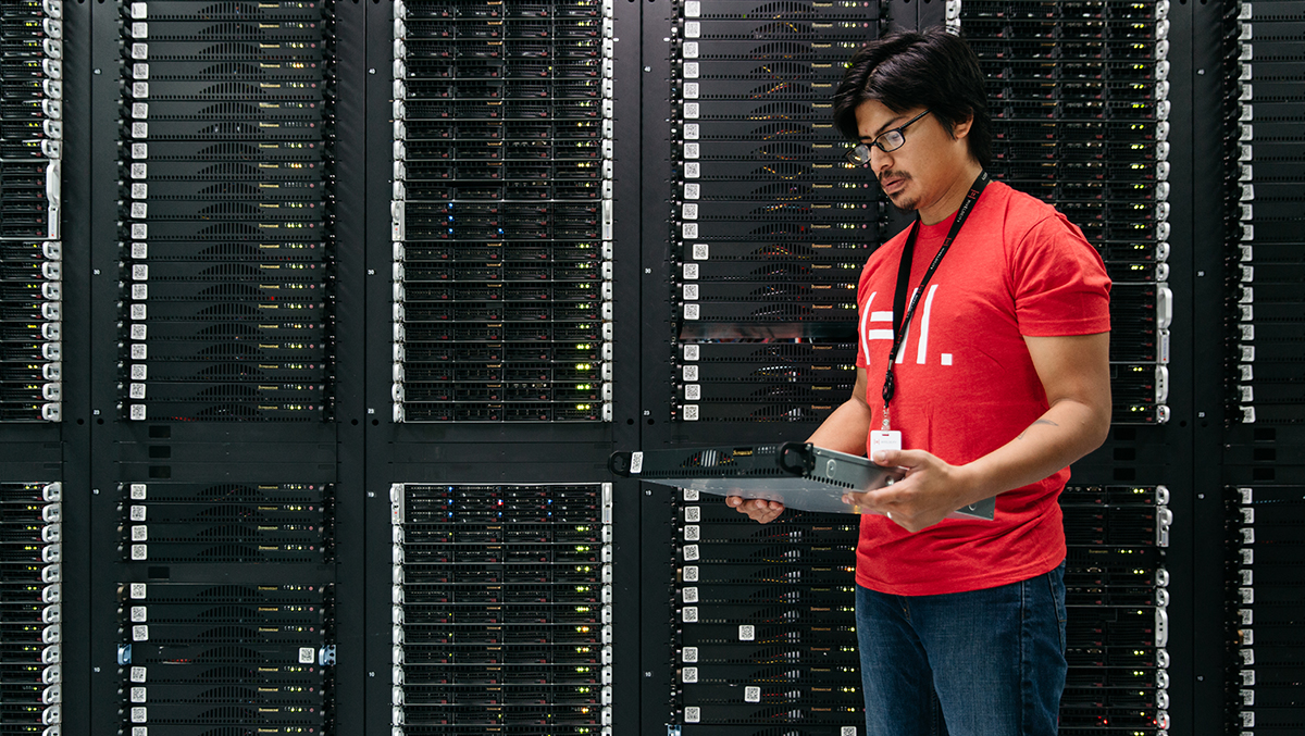 Image of a Hivelocity employee holding a bare metal server standing next to a rack of other servers